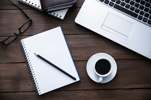 Desk with planner, notebook, laptop, and coffee cup